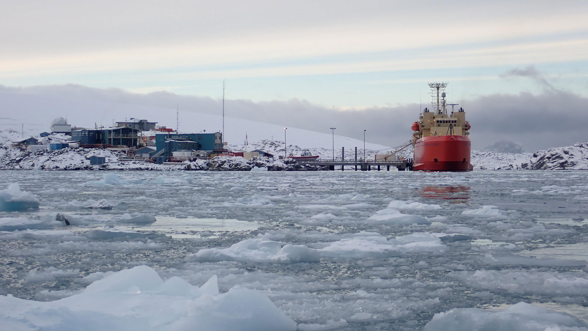 Ice chunks in the foreground, the red hulled ship at snowy Palmer Station. 