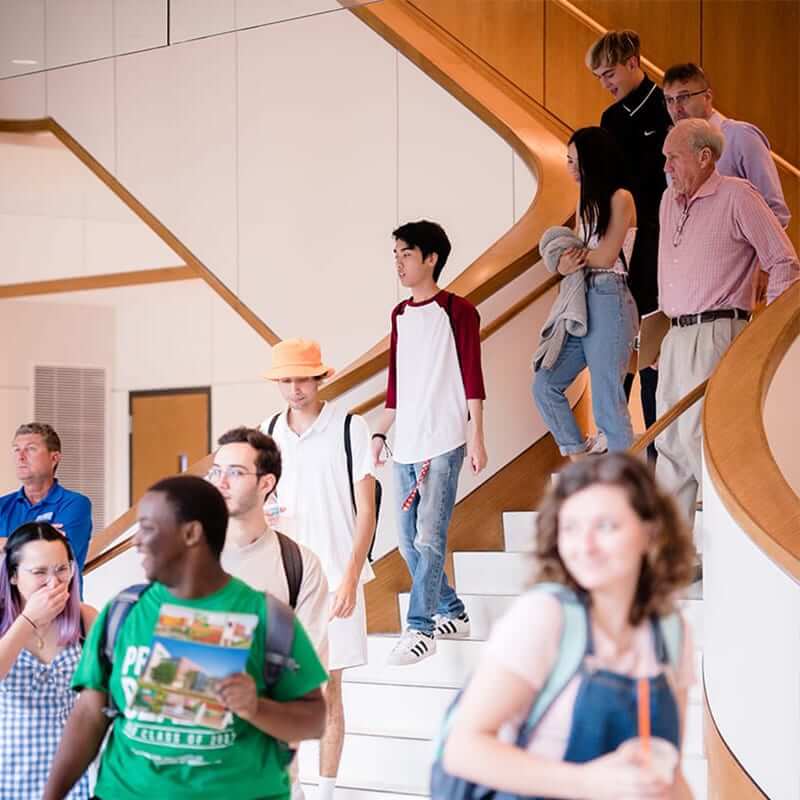 Students walking down the main stairwell in the Collat School of Business. 