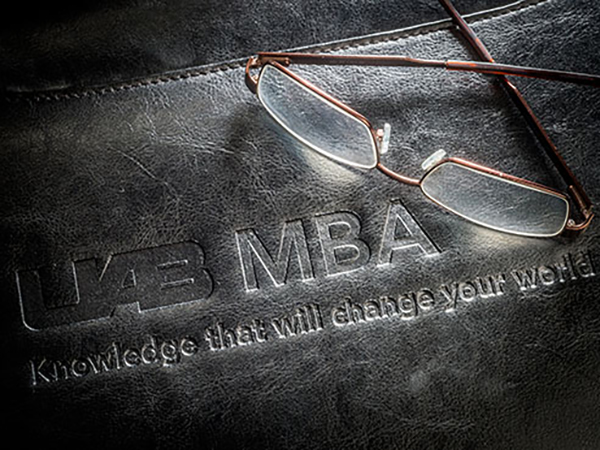 Glasses resting on black leather portfolio; cover says UAB MBA.