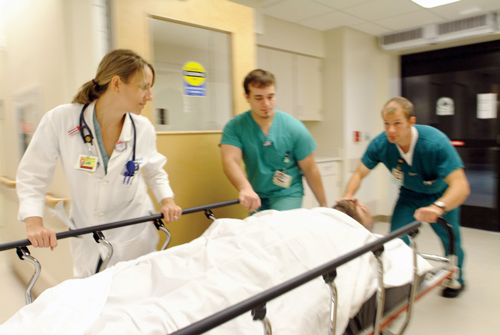 Three members of Emergency Medicine staff rolling unidentified patient into emergency room, 2008.
