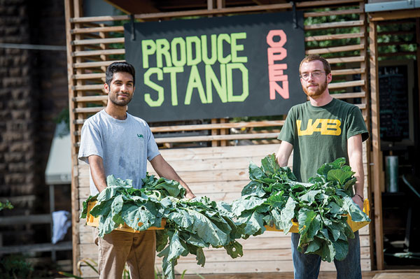Students holding plants while standing in front of produce stand.