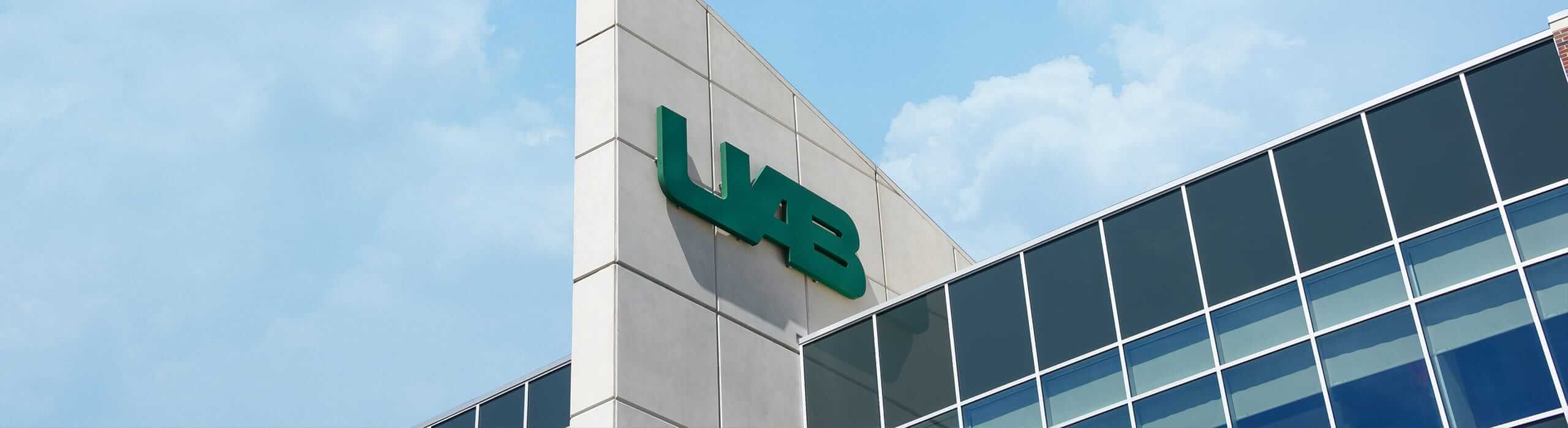 The UAB Logo on the Hill Student Center, with a blue sky and white clouds in the background. 