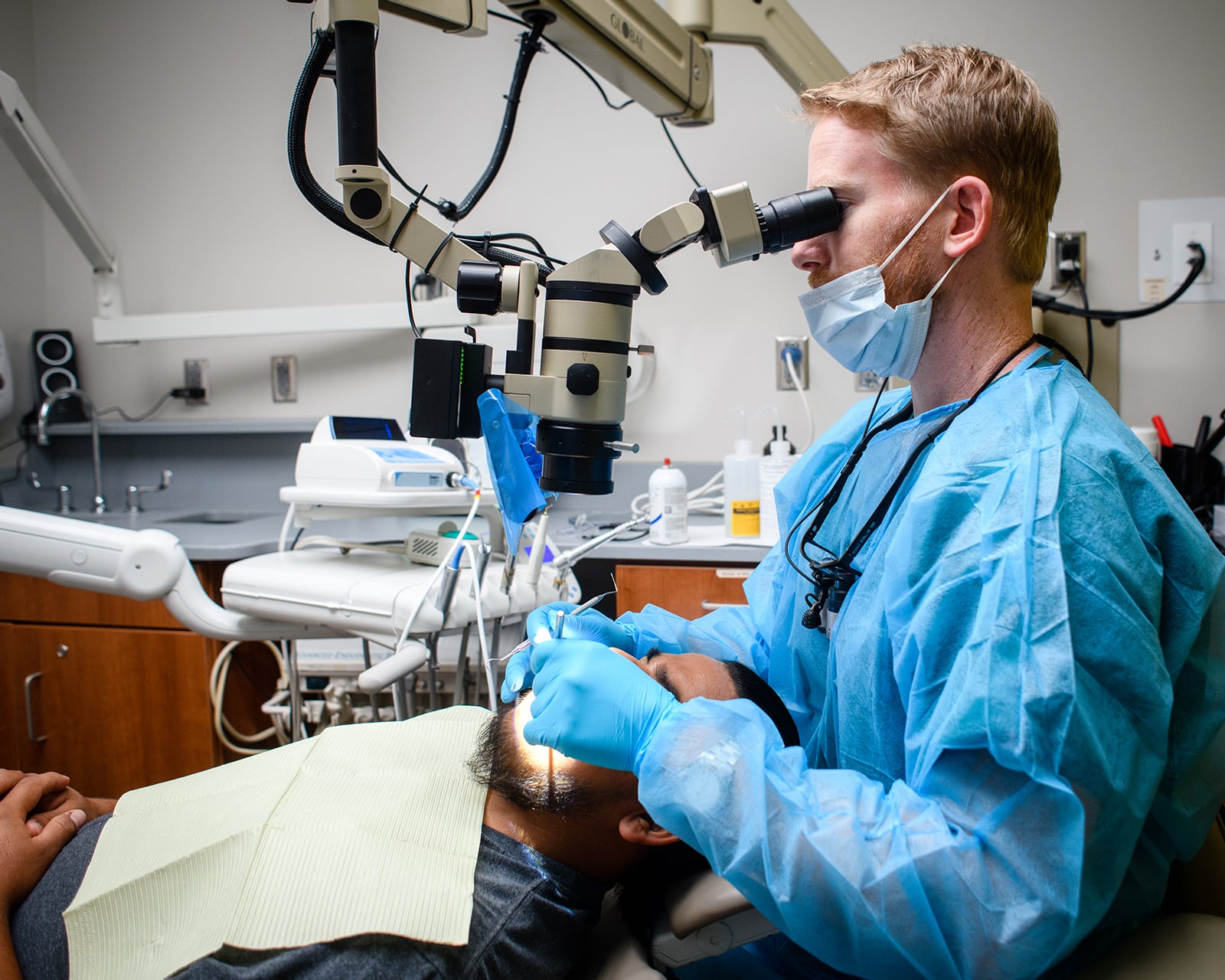 Dentist looking through magnifying device while working in a patient's mouth.