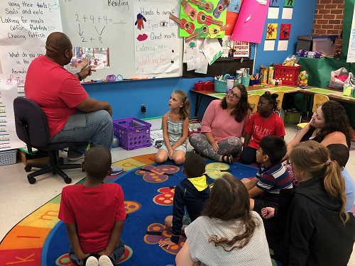 African American parent reading to elementary school children in a classroom