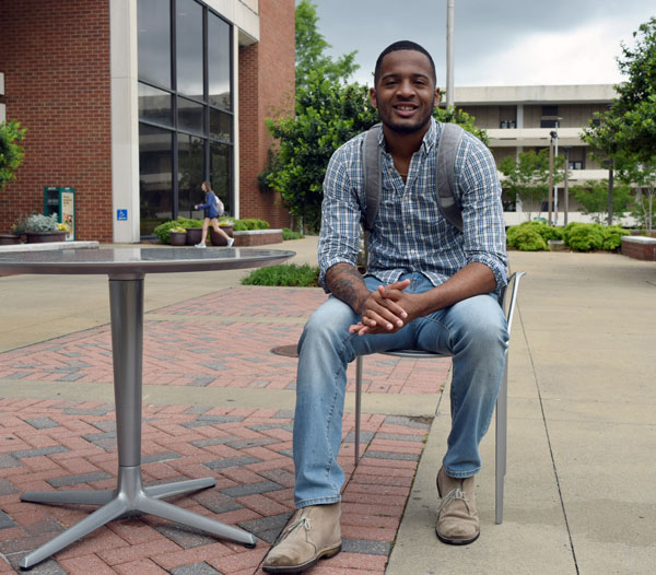 Rashad Hayes sitting at a table outside of a UAB building.