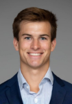 Dr. Wilson Fisher Professional headshot of a man wearing a navy suit jacket with a light blue shirt in front of a grey backdrop