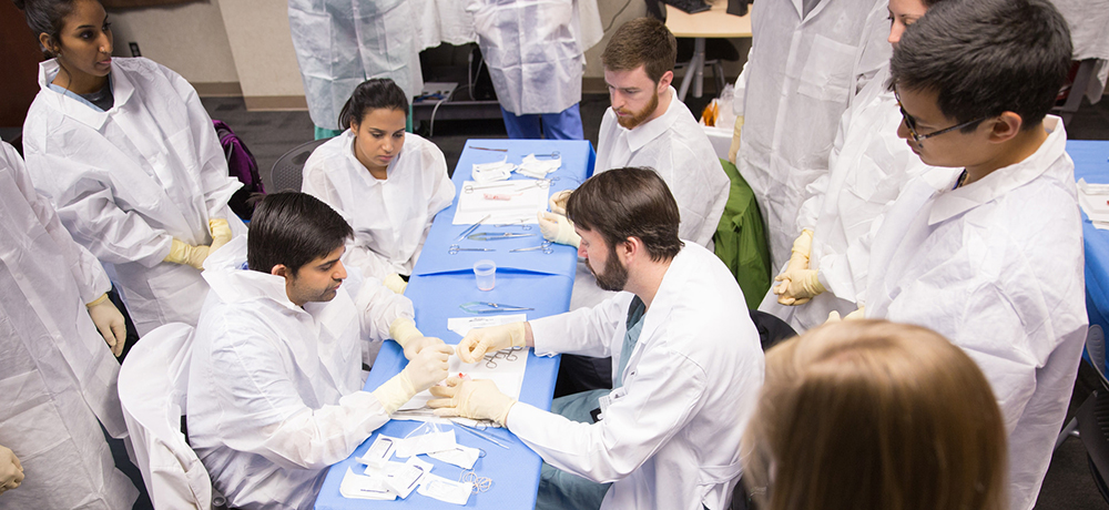 Division of Vascular Surgery and Endovascular Therapy Director Dr. Adam Beck teaches medical students about suturing at a vascular simulation activity.