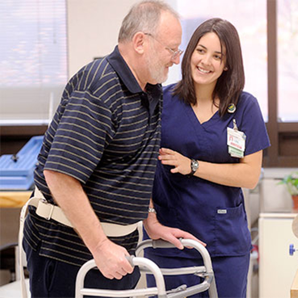 Physical therapist helps patient use a walker.