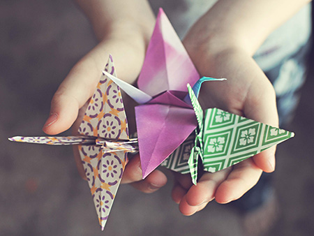 Boy holding three hand made origami cranes for Japan relief effort.