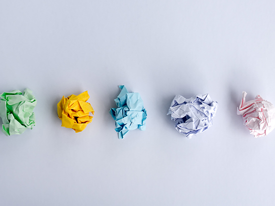 Five crumpled paper balls laying side by side in a horizontal line. 