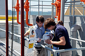 Senior engineering design students Kevin Nord (left) and Chris Yancey mount the wind turbine their team designed and constructed on a retractable pole atop the 18-story Alabama Power headquarters building. 