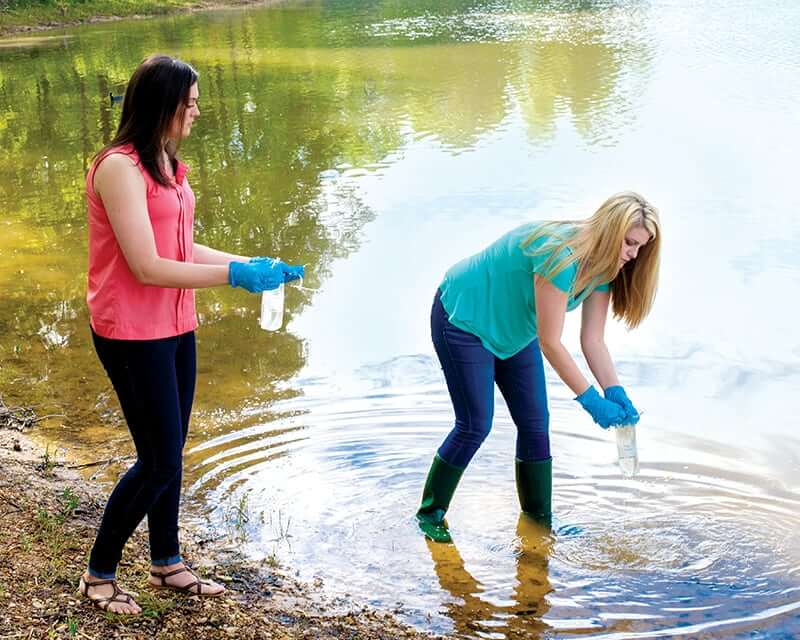 Two students taking samples from a river.