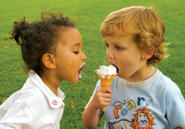 Photo of two children sharing an ice cream cone