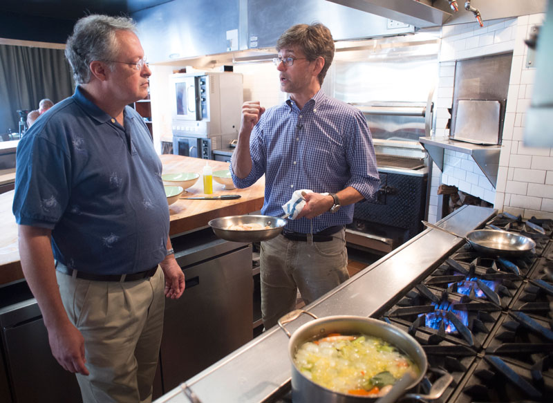 Photo of Stephen Watts and Chris Hastings discussing shrimp in kitchen