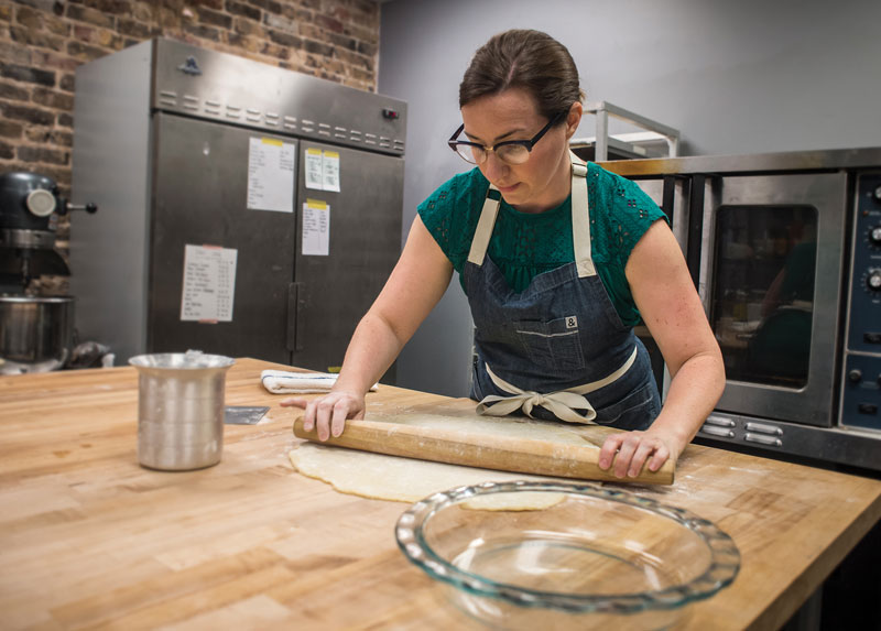 Photo of Kristen Farmer Hall rolling out dough in Feast & Forest kitchen