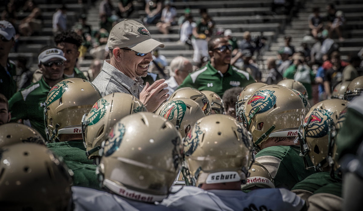 Photo of Coach Clark surrounded by players at the 2017 Spring Game