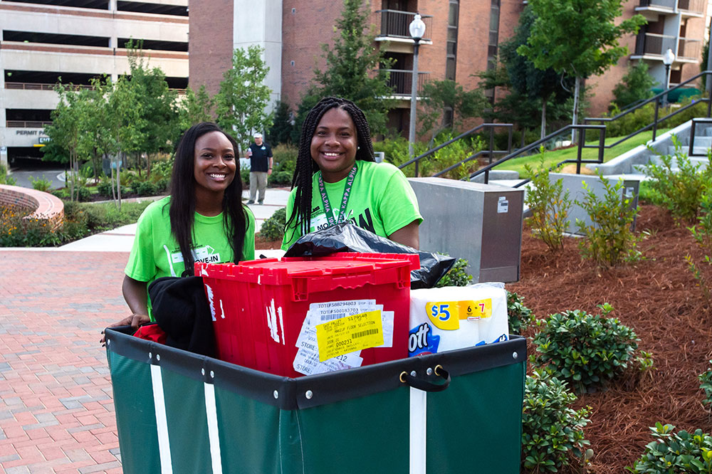 Photo of volunteers moving student belongings in cart