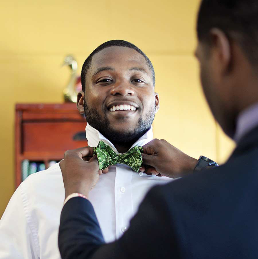 Photo of Booker Taylor III smiling while Tavaris Handley adjusts his green bow tie