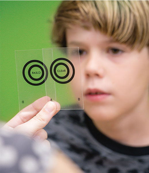 Photo of young patient looking at clear cards with circles on them
