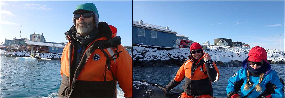 Chuck in green hat and orange coat, Hannah wearing a blue and black drysuit and red hat and Jami in orange coat and red hat smile as zodiacing away from Palmer Station, seen in background