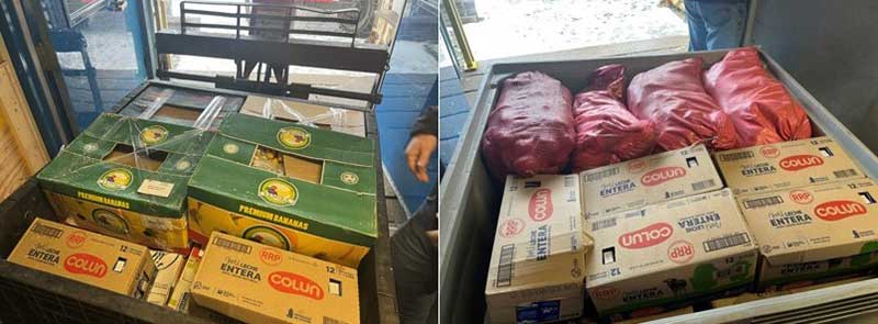 A pair of large gray plastic boxes loaded with several green cardboard boxes boasting fresh bananas, numerous cases of Entera cartons of milk and four red meshed bags of potatoes