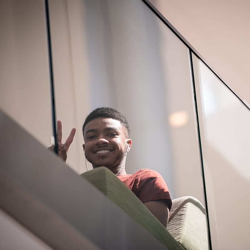 A black male student waving from a balcony. 