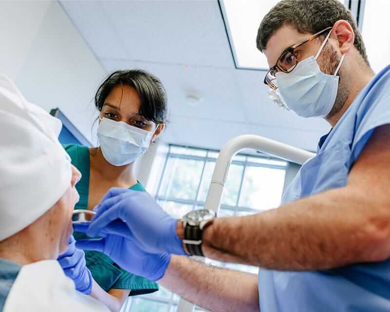 A male and female dentist conducting an exam. 