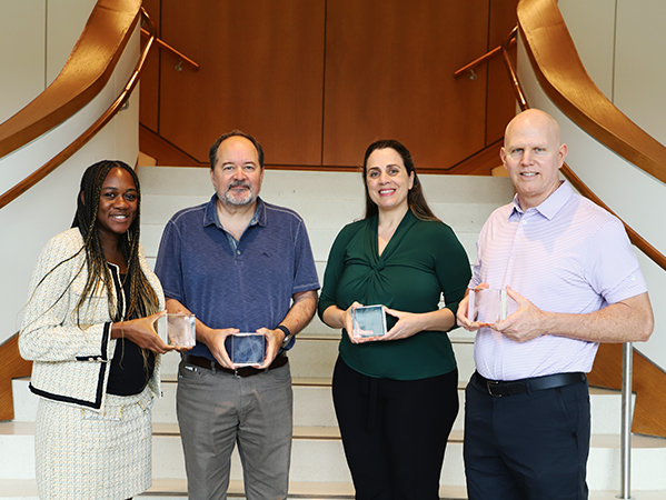 Four business faculty members holding awards