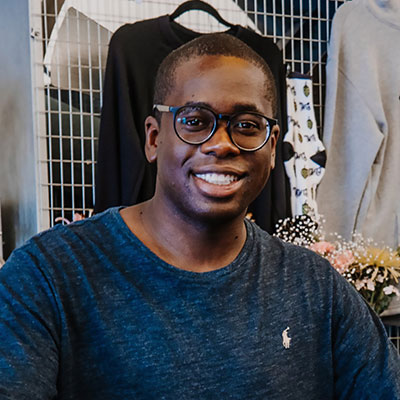 close photo of a man smiling in a blue shirt and glasses