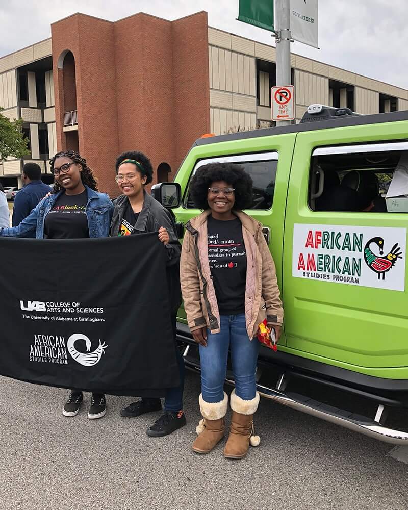  Three AASSO members at a UAB Homecoming parade holding the AASSO banner. 