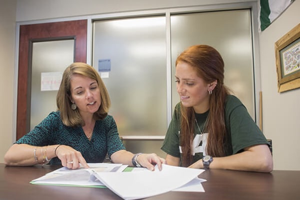 Advisor with undergraduate student in an advising session reviewing documents.
