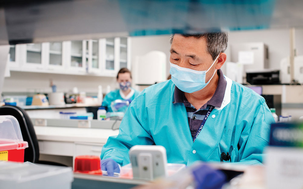 Masked Asian male working in one of UAB's labs. 