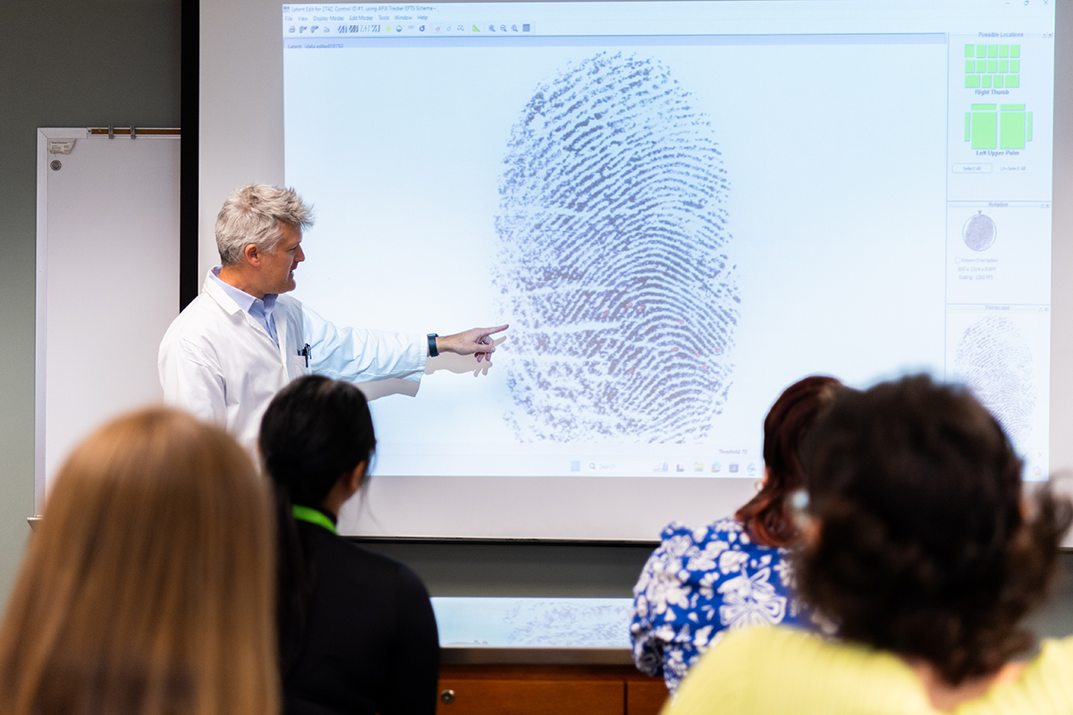 UAB Forensic Science Teaching Lab, University Boulevard Office Building. Staged shoot showing Dr. Jason Linville, PhD (Associate Professor, Criminal Justice) is giving a lecture to seated students about how to identify and mark minutia in a fingerprint during analysis, October 2024.