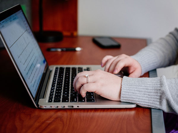 Closeup of student's hands typing on a laptop. 