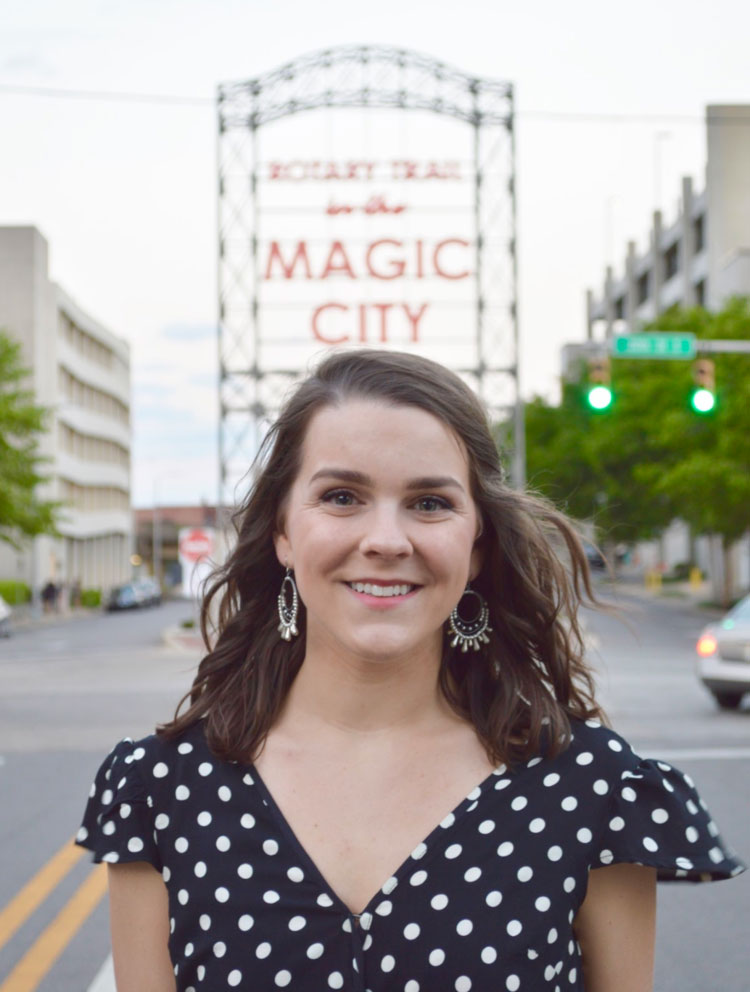 Kacey Keith standing in front of the Rotary Trail's "Magic City" sign. 