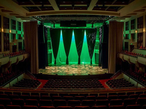 The main stage at the Alys Stephens Center, with stage curtains and green illumination. 