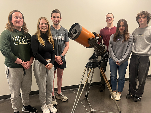 Photo of the Astronomy Club posing with a telescope