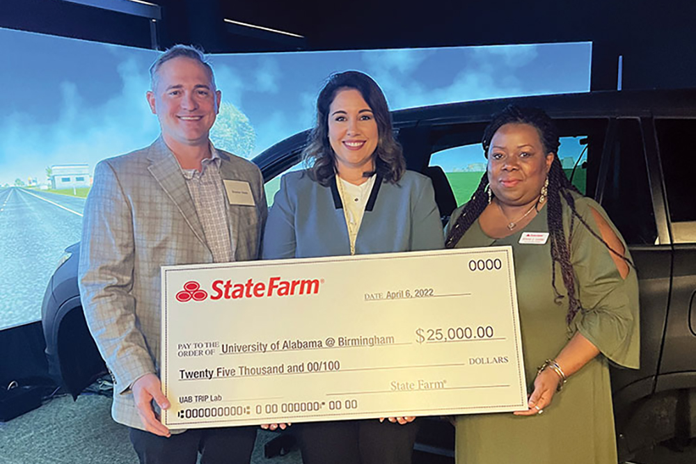 State Farm employees and Dr. Stavrinos hold a large display check for 25 thousand dollars. 