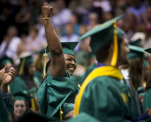A student raises a triumphant fist at her UAB graduation ceremony. 