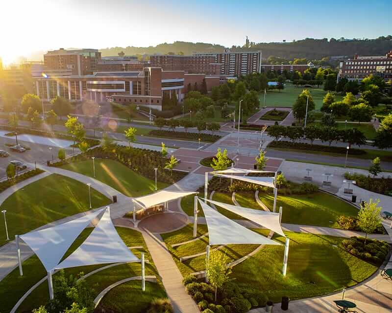 Drone shot of a campus green space with sail-like shelters. 