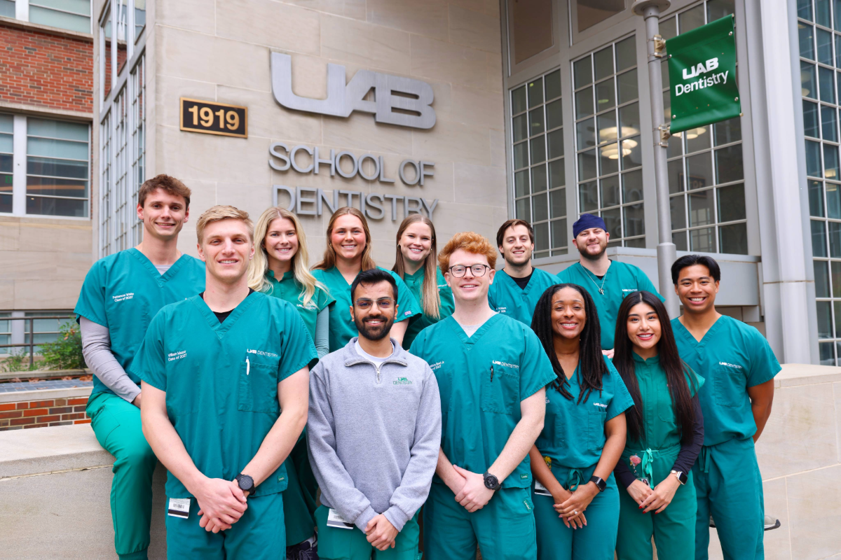 Group of dental students in the Rural Dentistry Club smiling for photo in front of UAB School of Dentistry