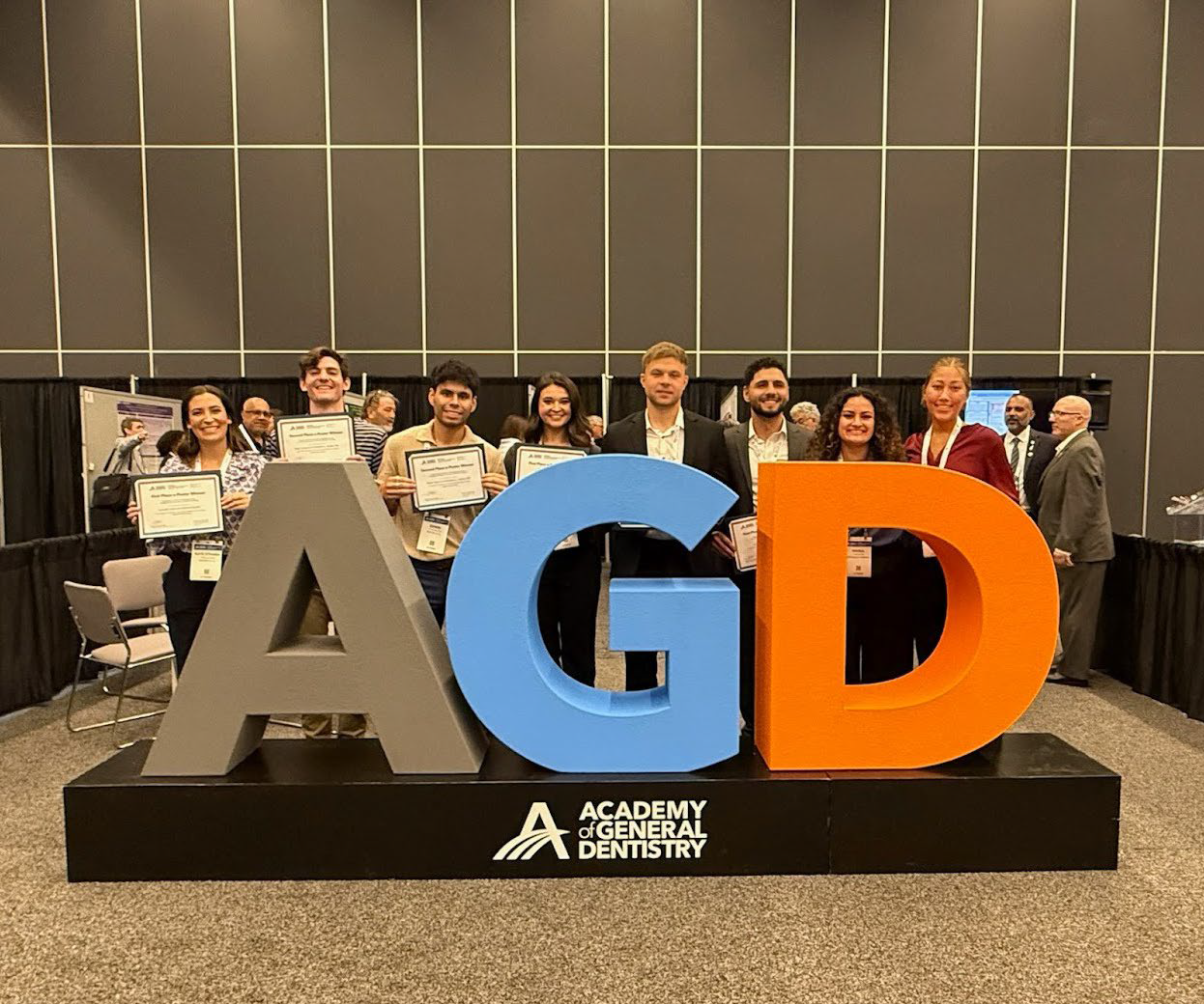 UAB dental students holding awards in front of AGD sign at AGD Scientific Session 2025