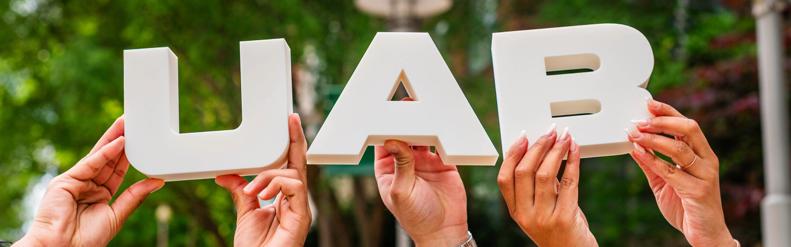 Hands holding up block letters spelling out 