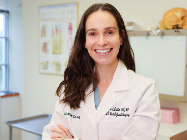 Woman in white coat smiling in clinical setting