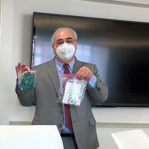 Dean Taichman holding masks while wearing a mask.