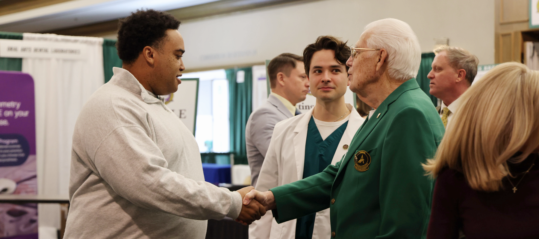 Alumni member shaking hands with student at conference