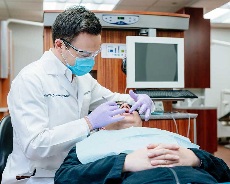 Close up of gloved hands cleaning the mouth of a patient.