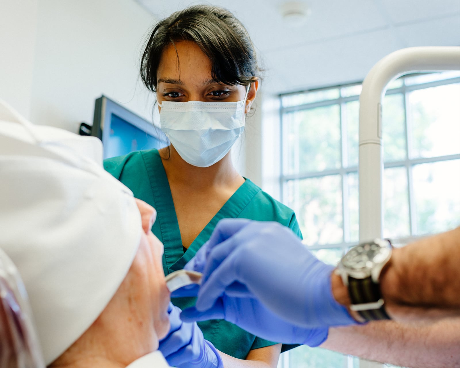 Dentist in a mask examining a patient's mouth.