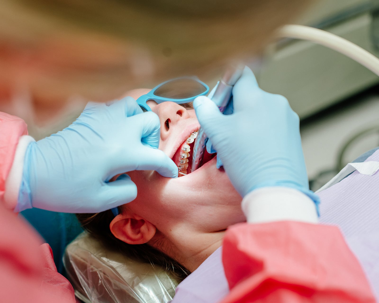 Dentist examining the mouth of a girl with braces.