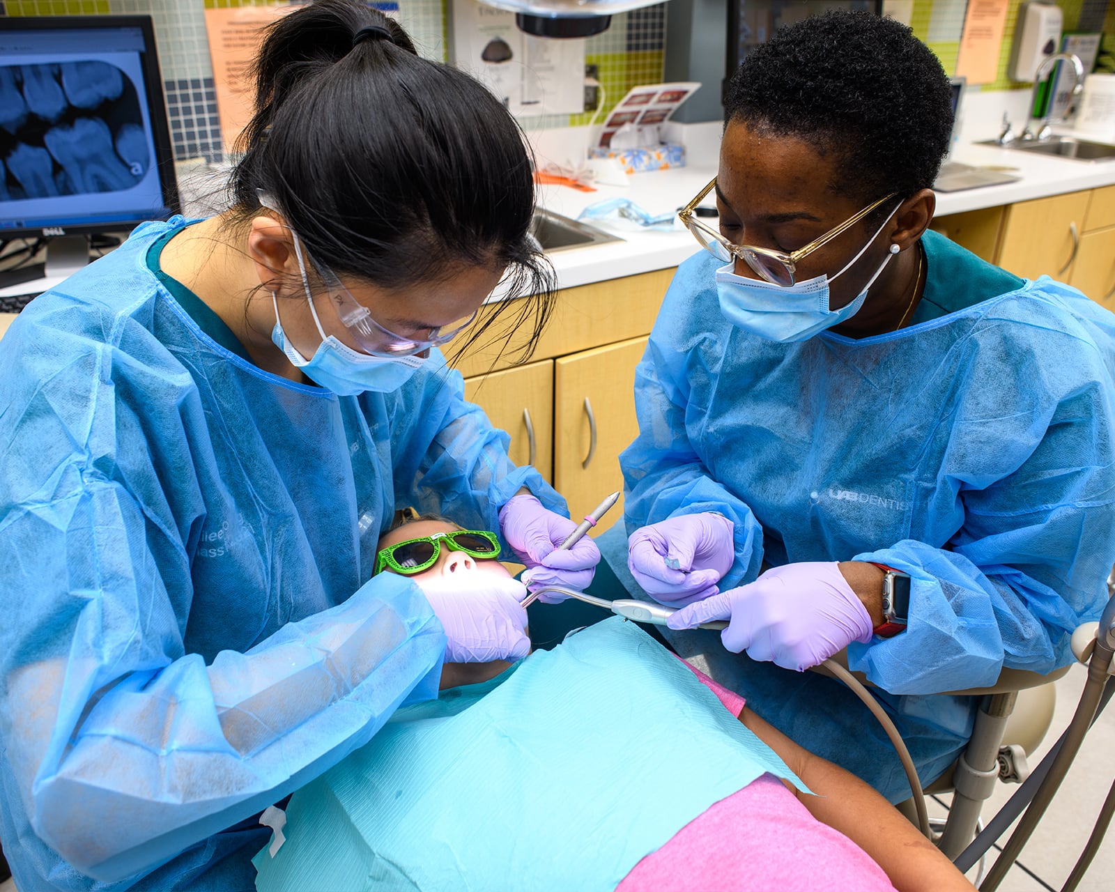 Two dentists examining a young girl's mouth.